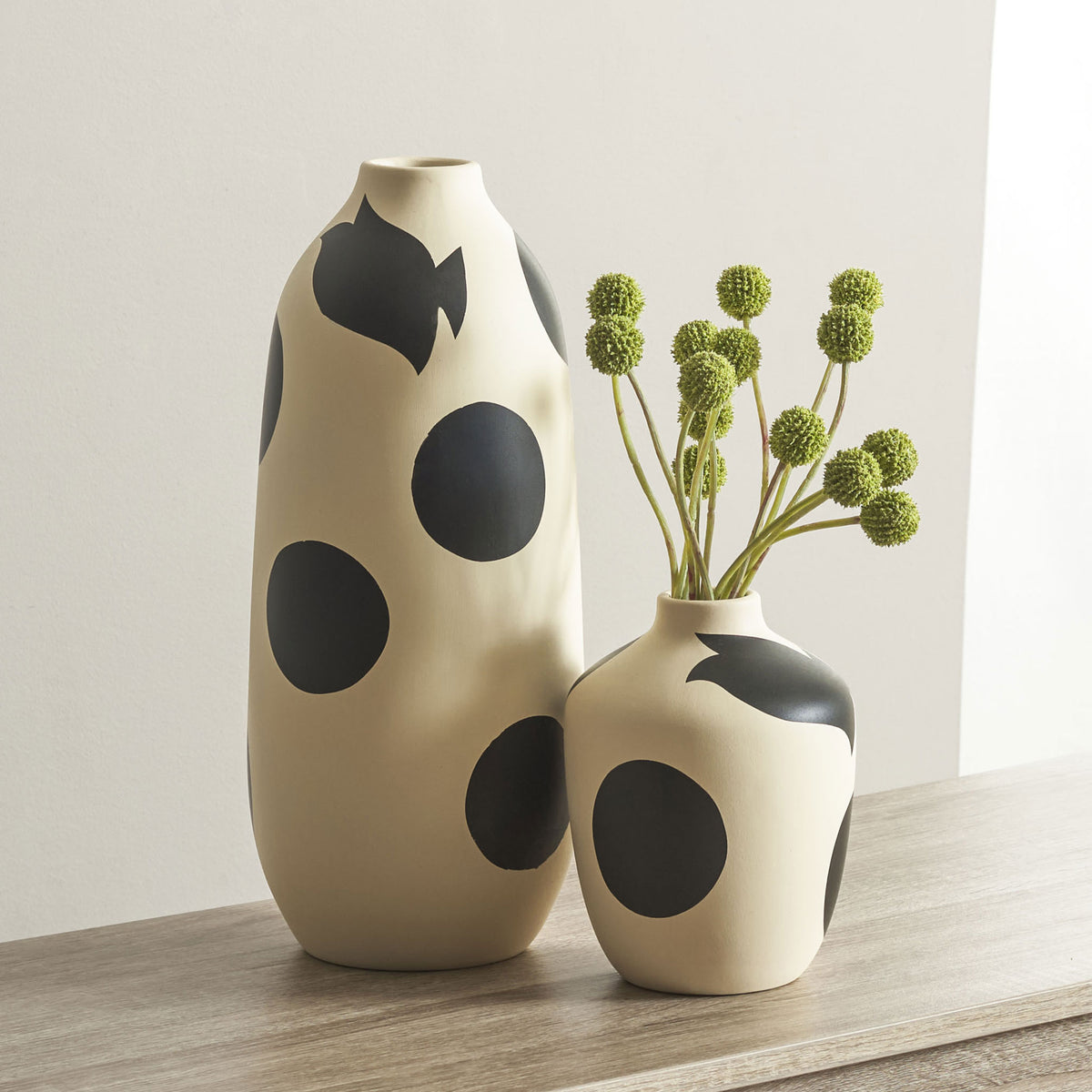 Black-spotted cream ceramic vases bring sculptural contrast to a tabletop, with greenery in the smaller vase. || RDC4027A-SET2 || front_room