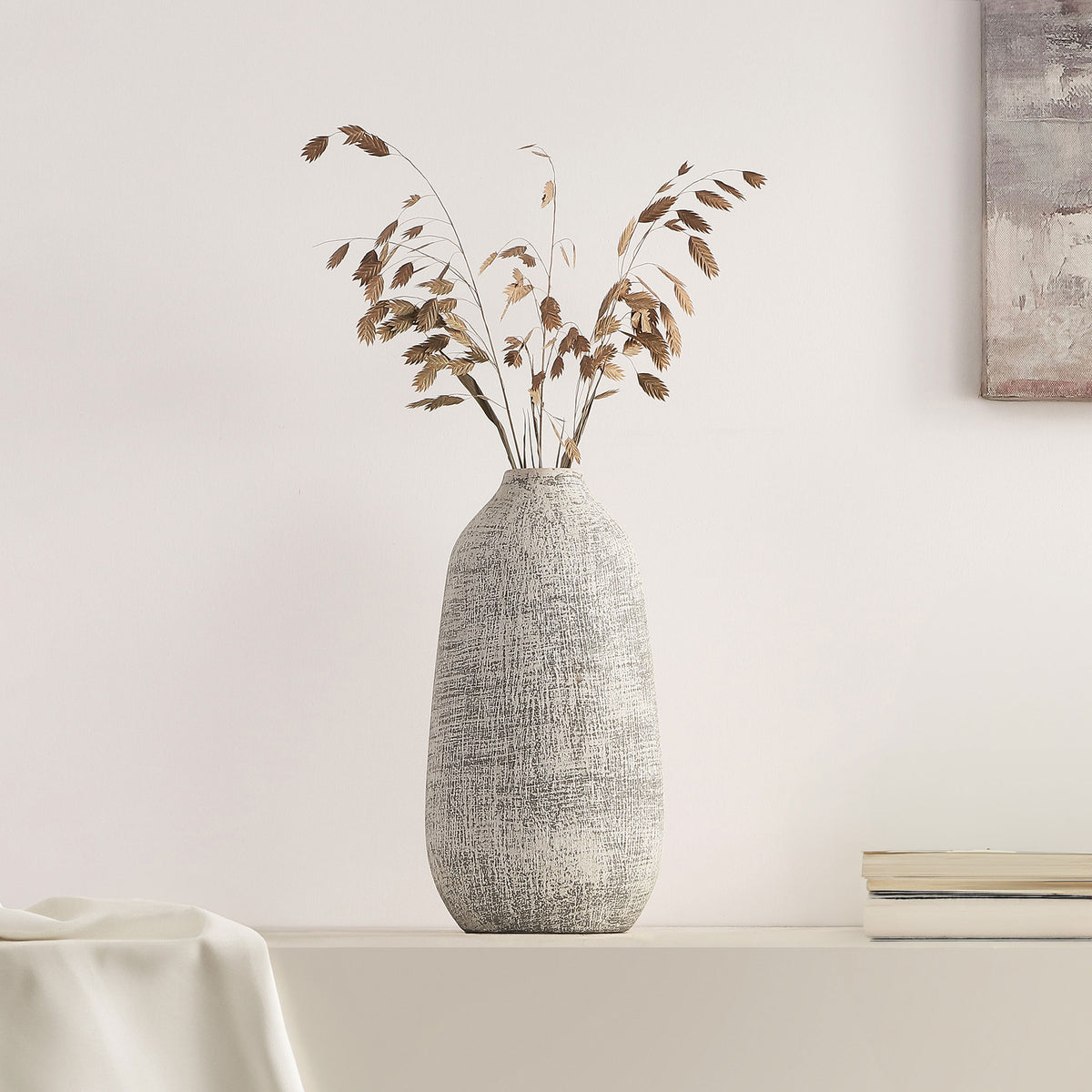 A whitewashed gray ceramic vase holds airy dried branches on a minimalist shelf || RDC4031A || front_room
