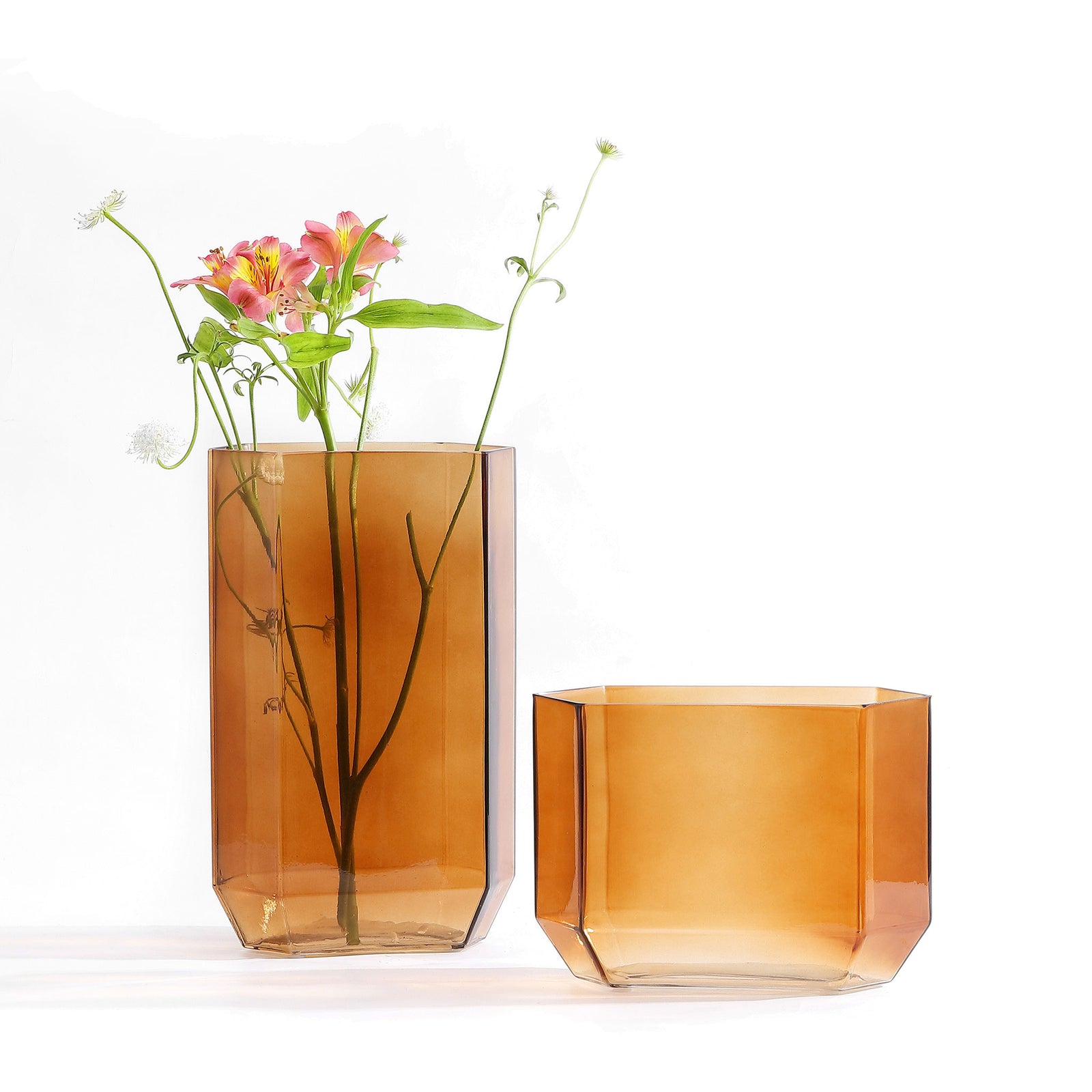 Vibrant blooms rise from the taller of two translucent amber glass vases, paired with a shorter, wide companion. || RDC4035B-SET2 || front_studio