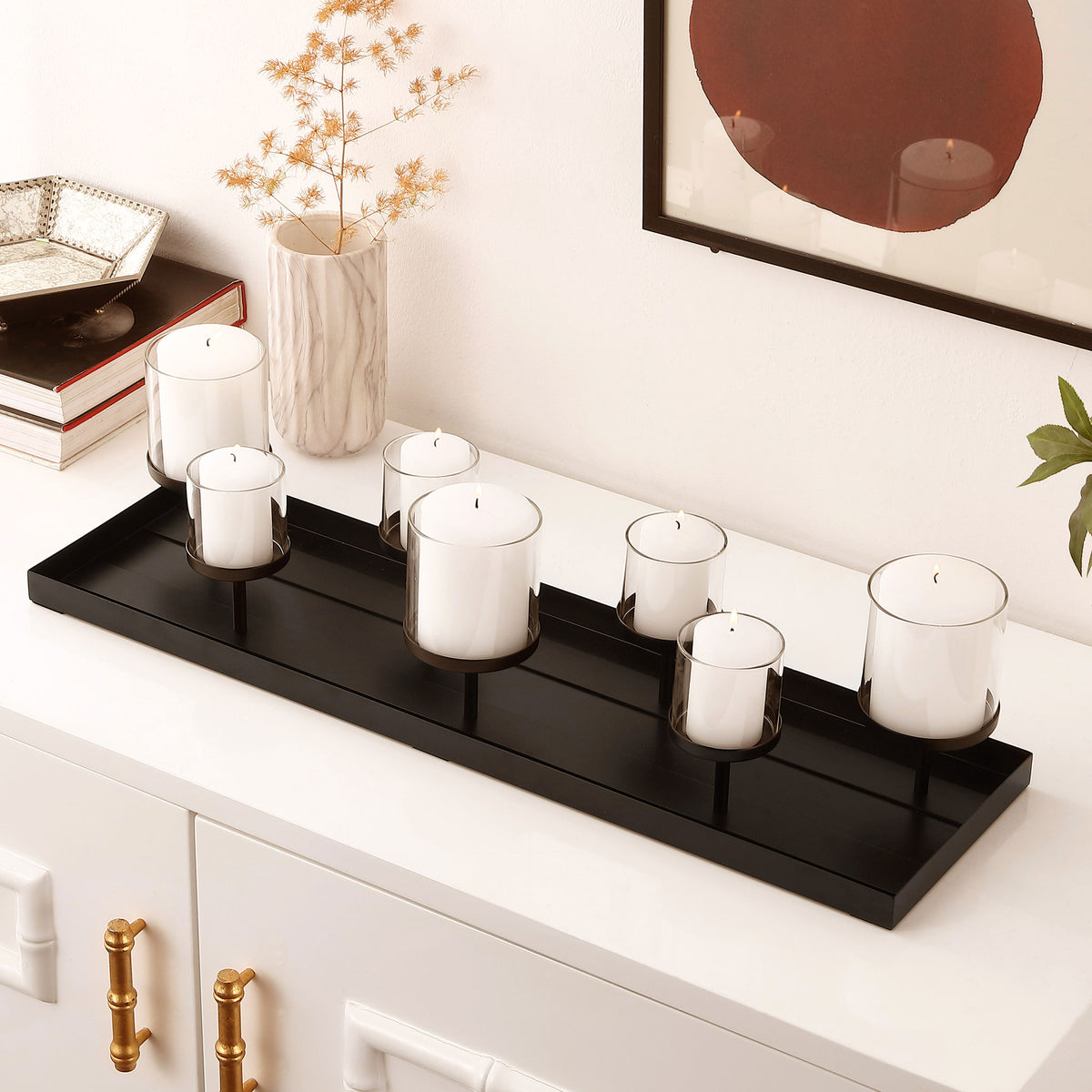 White pillar candles sit in glass cups above a sleek black tray, adding warmth to a modern console. || RDC4040A || front_angle_room