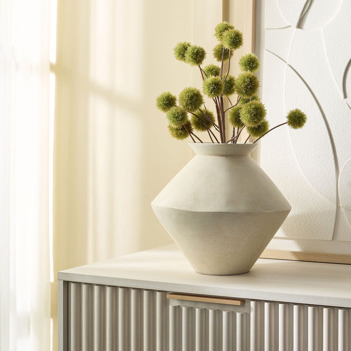 Sculptural cream vase holds green stems atop a console || RDC4045A || front_room