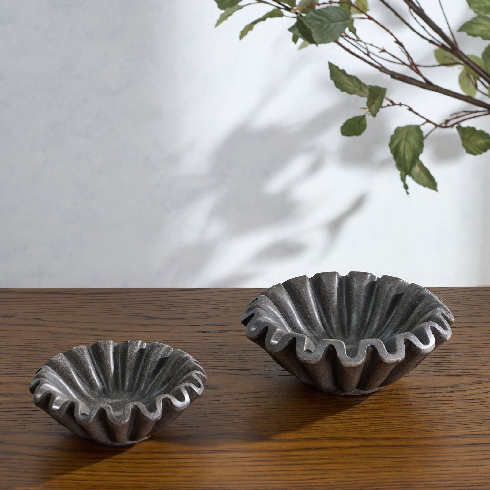 A large charcoal bowl and smaller companion display wavy edges and deep fluting on a warm wood surface. || RDC4052B-SET2 || front_angle_room