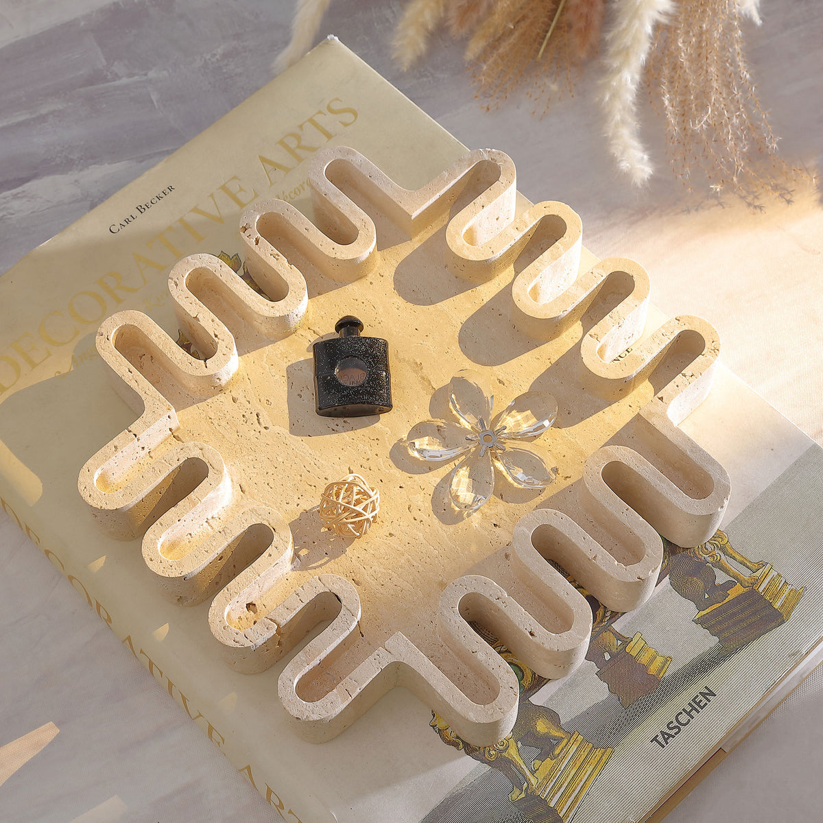 Tan travertine tray displays small keepsakes within its sculptural, wavy-edged square form. || RDC4055A || top_angle_room