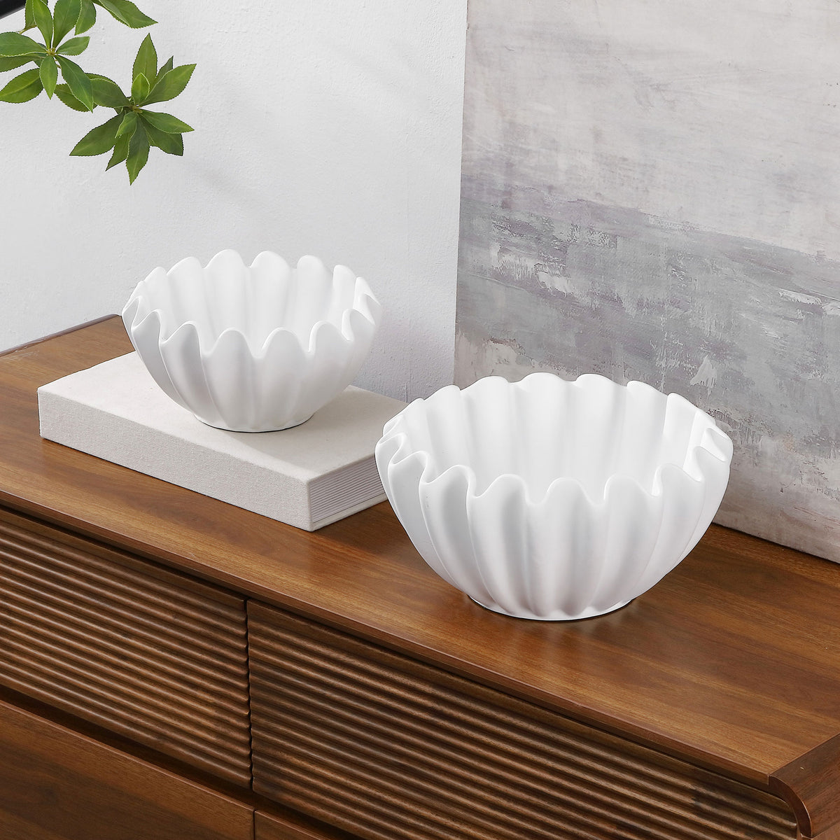 White ruffled bowls bring a sculptural accent to a wood console, with one elevated on books.