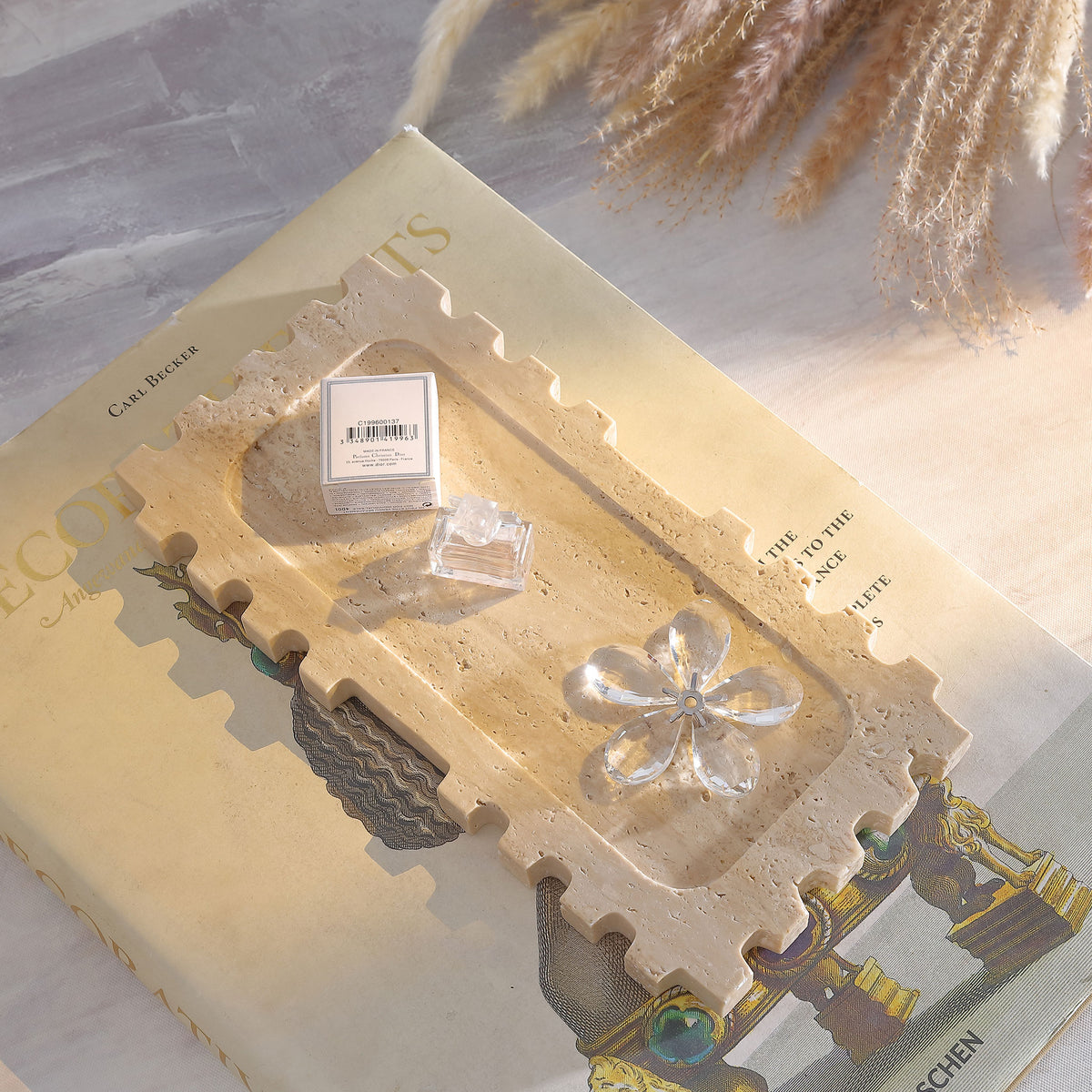 A tan travertine tray displays glass accents atop a stack of books. || RDC4057A || front_angle_room