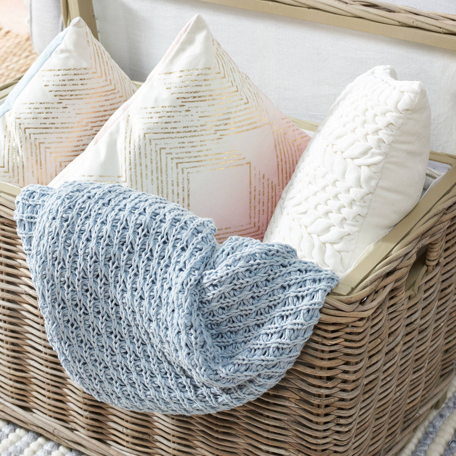 A gray rattan storage trunk keeps pillows and a blue knit throw tucked neatly inside. || SEA7018A || storage_open_room