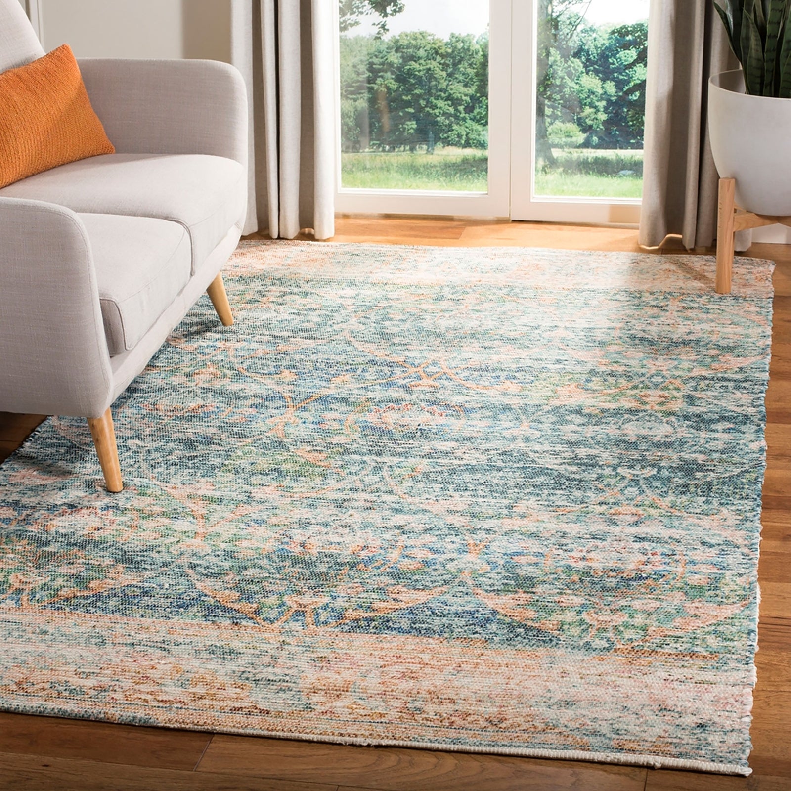 Turquoise and peach distressed area rug with faded ornamental motifs in a bright living room || SFN563A-5 || top_angle_room