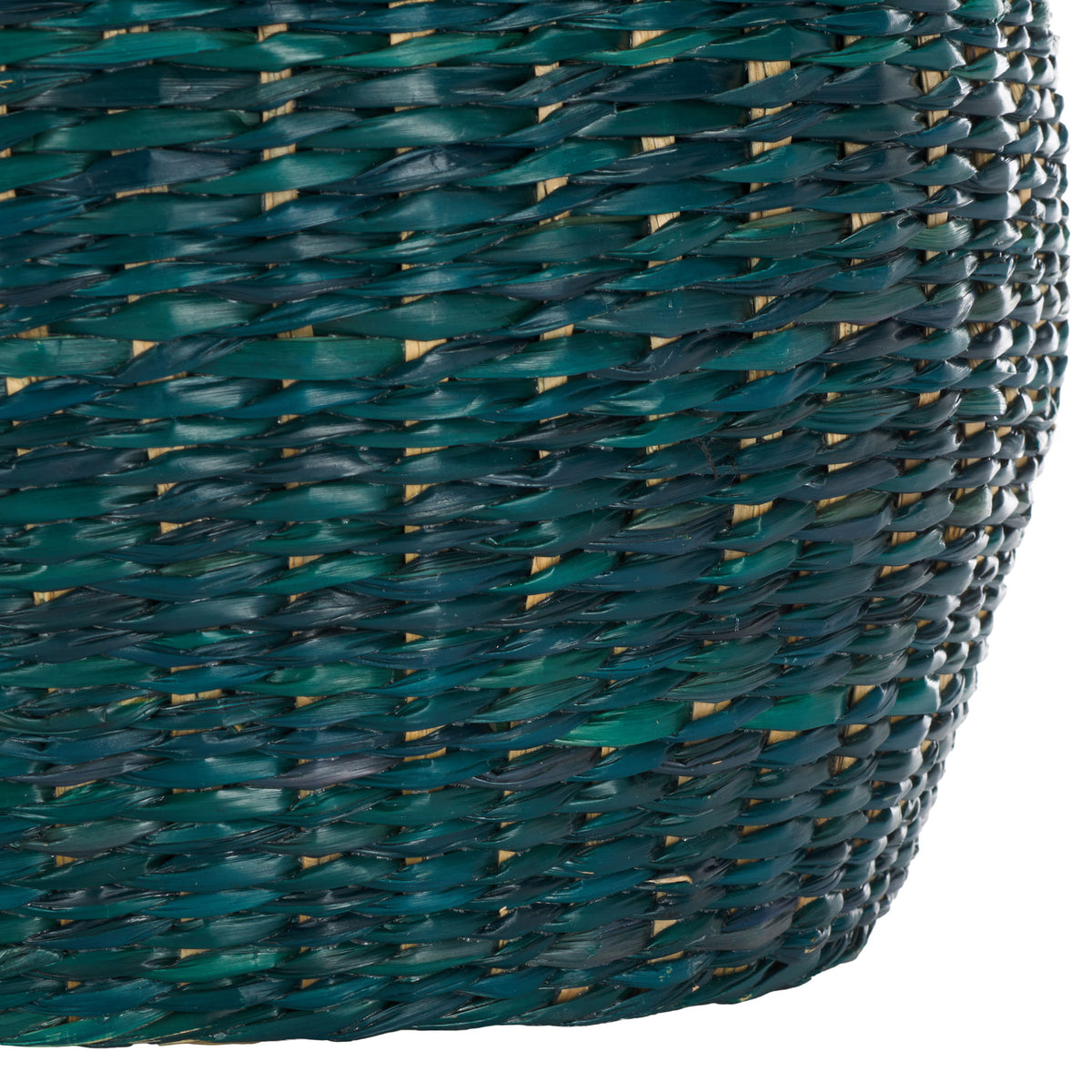 The basket's rounded base continues its dense green seagrass weave to the floor