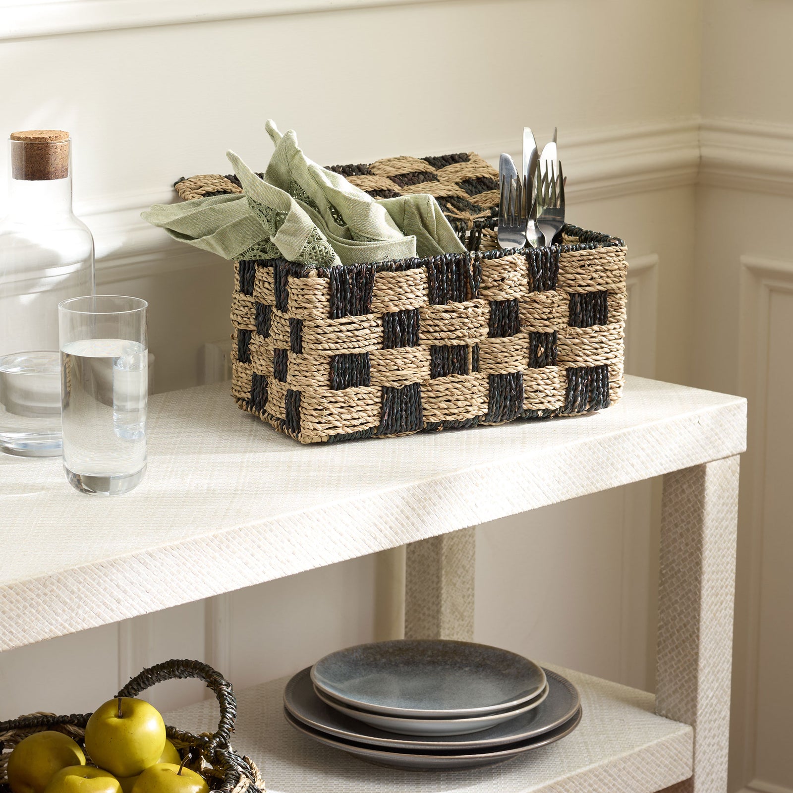 An open woven basket keeps napkins and flatware handy within its two-tone checkerboard design. || STG1822A || front_angle_open_room