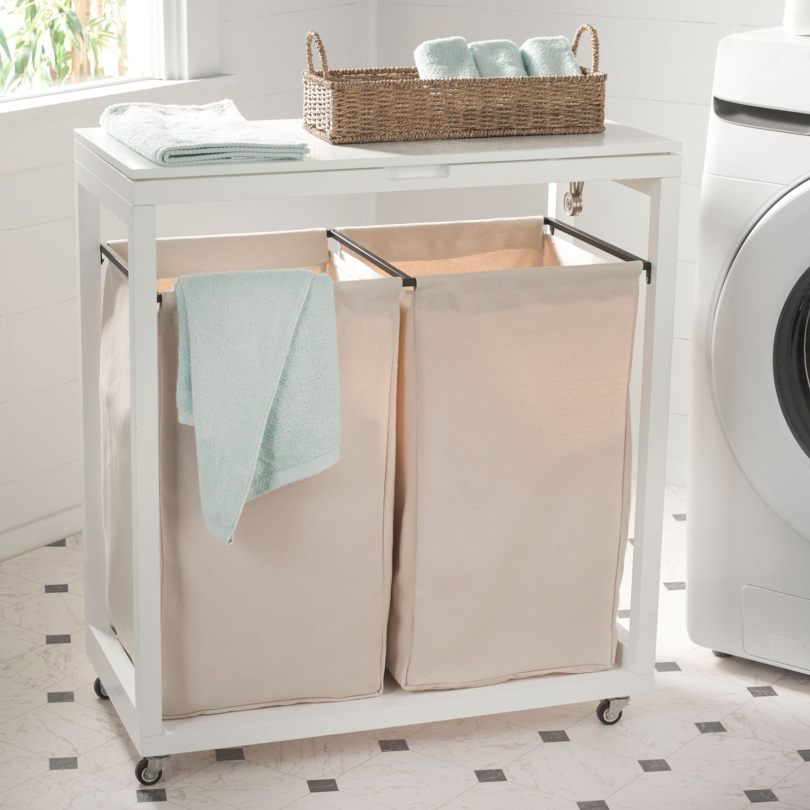 A white lid provides space for folded towels above twin beige fabric laundry bins on casters. || STG1900A || front_angle_room