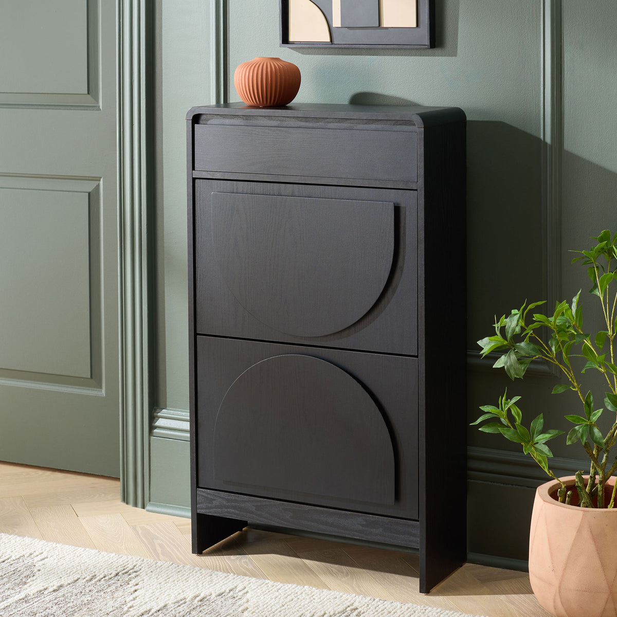 A slim black shoe cabinet with two arched panels brings tidy storage to an entryway. || STG3100B || front_angle_room