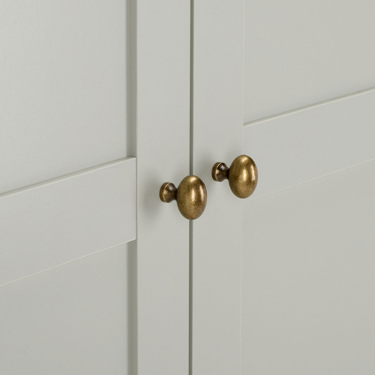 Rounded brass-tone knobs add warmth to the light gray paneled doors. || STG3102A-2BX || handle_studio