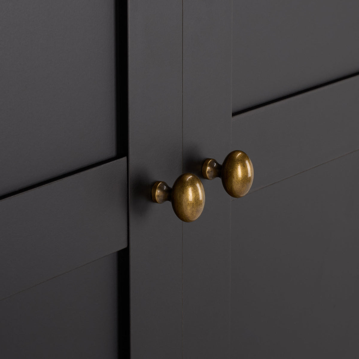 Rounded brass-tone knobs bring warm contrast to black paneled doors. || STG3102C-2BX || handle_studio