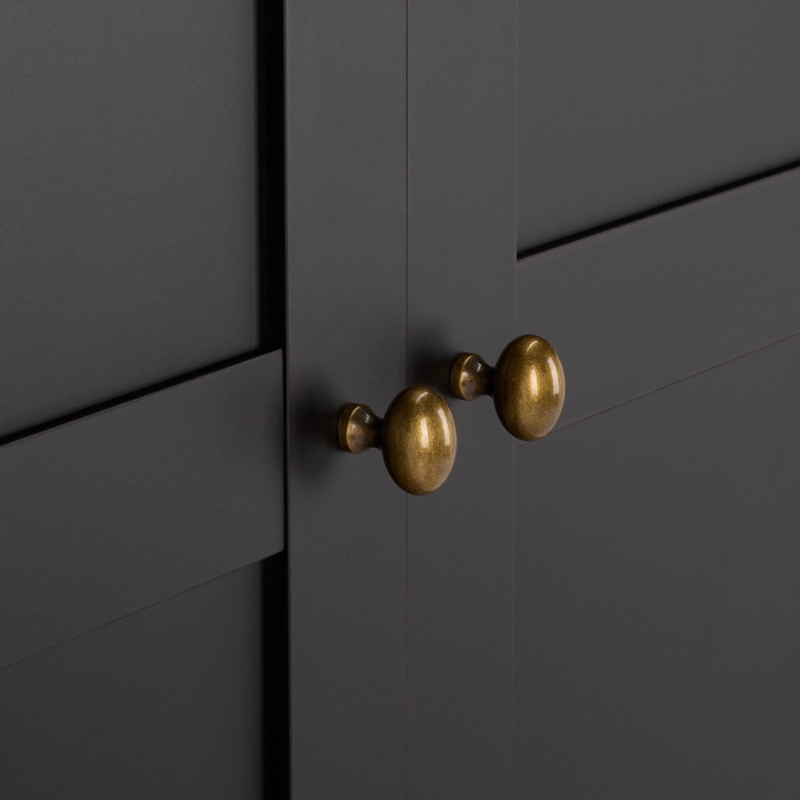 Rounded brass-tone knobs bring warm contrast to black paneled doors. || STG3102C-2BX || handle_studio