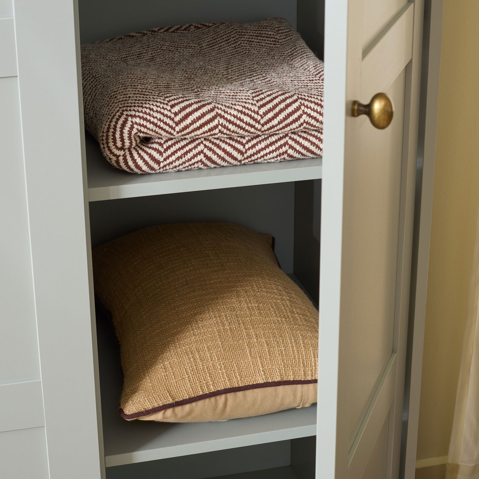 Open light gray shelves hold folded blankets and pillows behind a paneled door. || STG3103A-3BX || storage_open_room