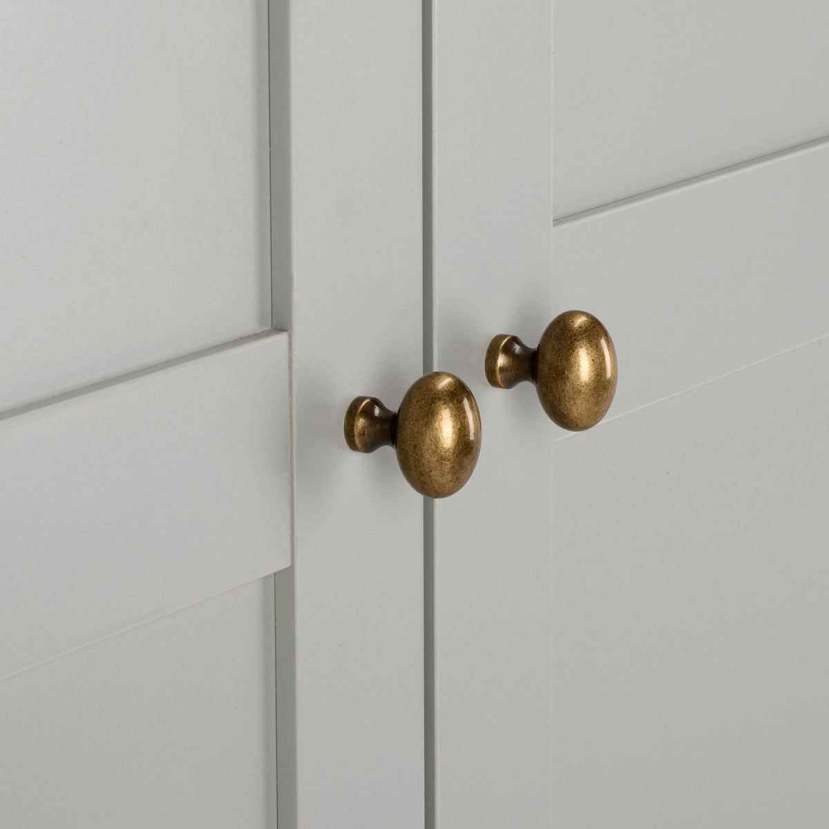 Rounded brass-tone knobs add contrast to smooth light gray paneled doors. || STG3103A-3BX || handle_studio