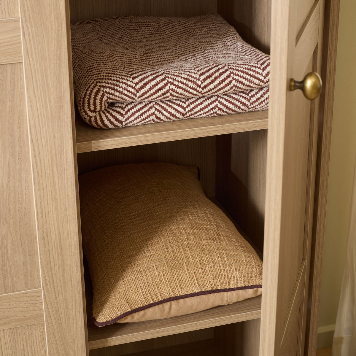 Natural wood-look shelves hold folded bedding behind an open paneled door. || STG3103B-3BX || storage_open_room