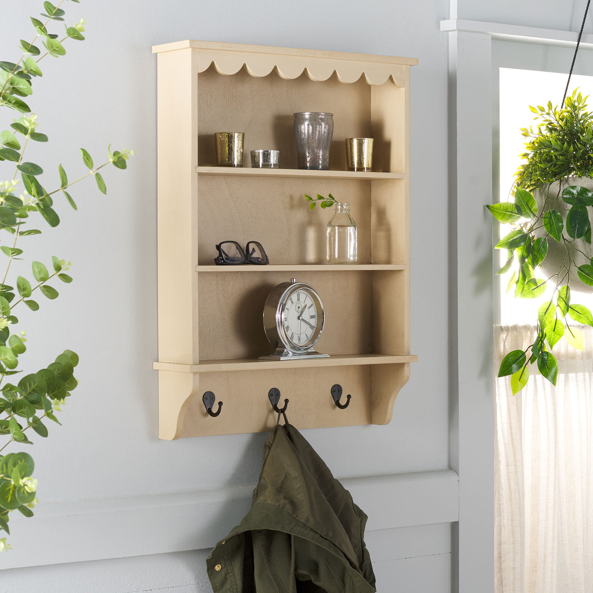 Pale wood shelves hold decorative accents while a black hook keeps a jacket handy