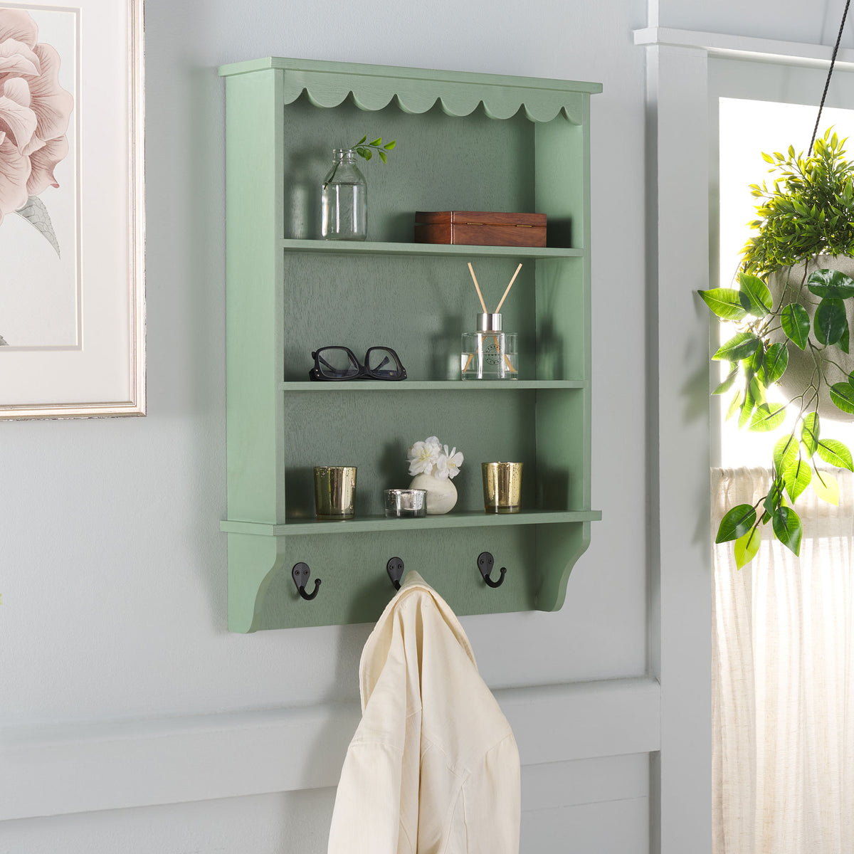 Sage green shelves display plants and accents, with a light jacket hung from a hook