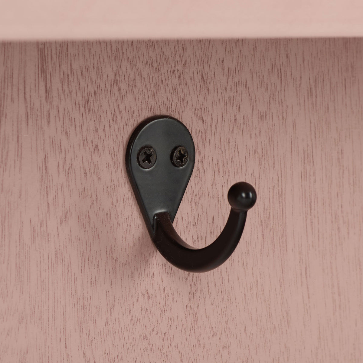 A curved black metal hook stands out against softly grained pink wood || STG5702E || detail_studio