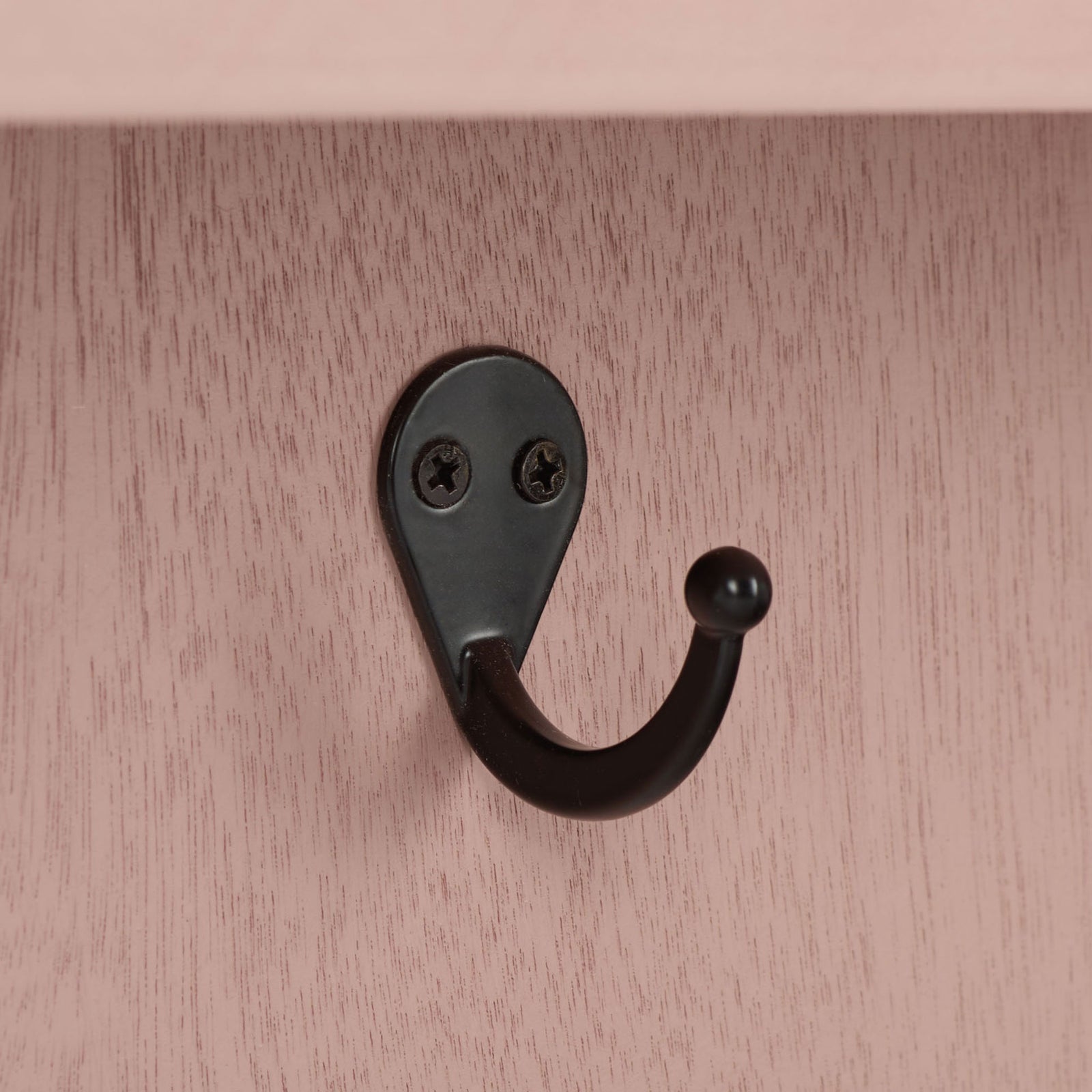 A curved black metal hook stands out against softly grained pink wood || STG5702E || detail_studio