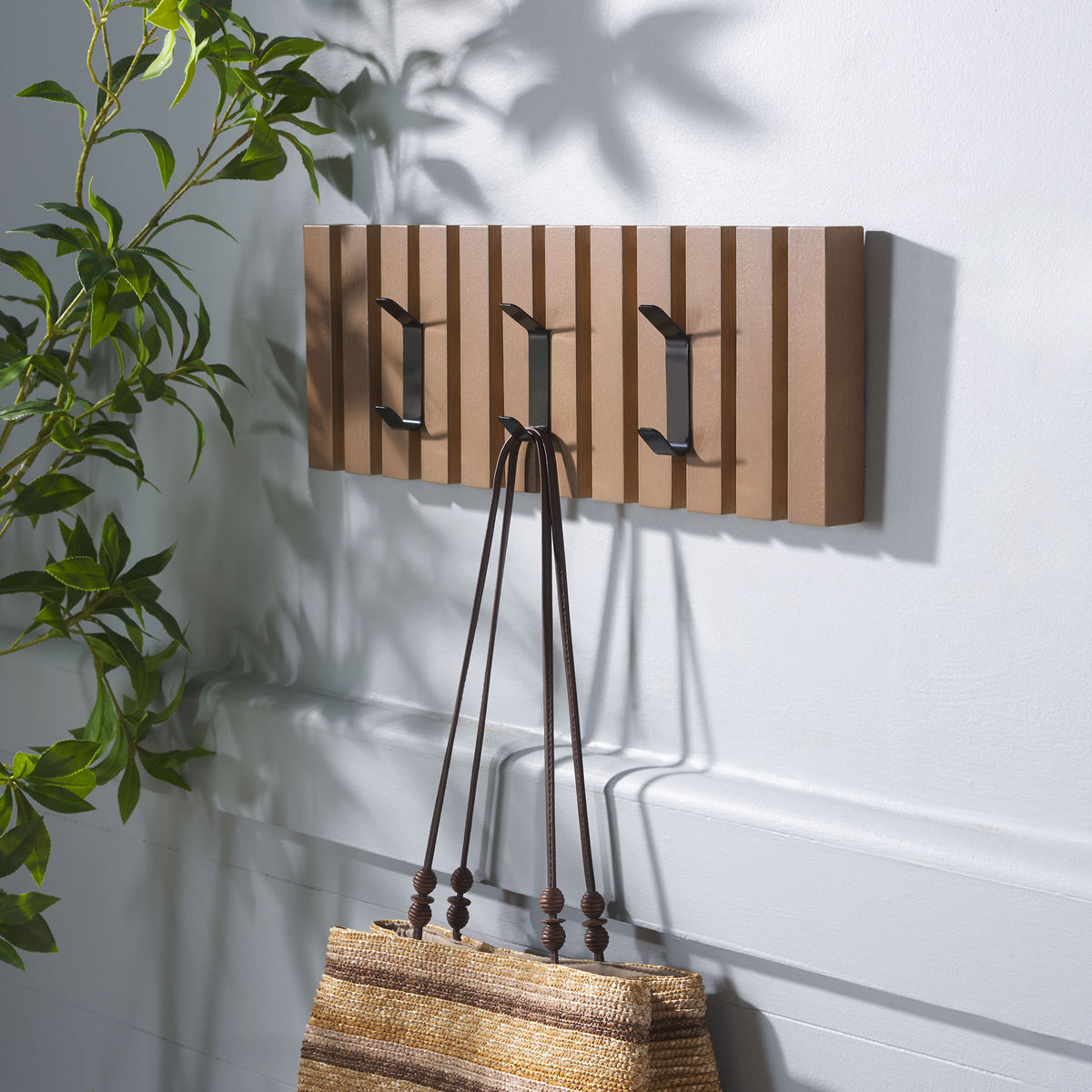 A woven tote hangs from the sepia wood rack, leaving two more black hooks ready for daily layers. || STG5704B || front_angle_room