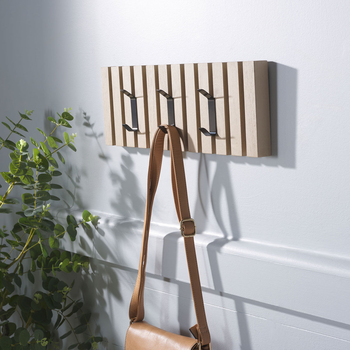 A tan shoulder bag hangs from the sand-finished rack, with two extra hooks ready for jackets or hats. || STG5704N || front_angle_room