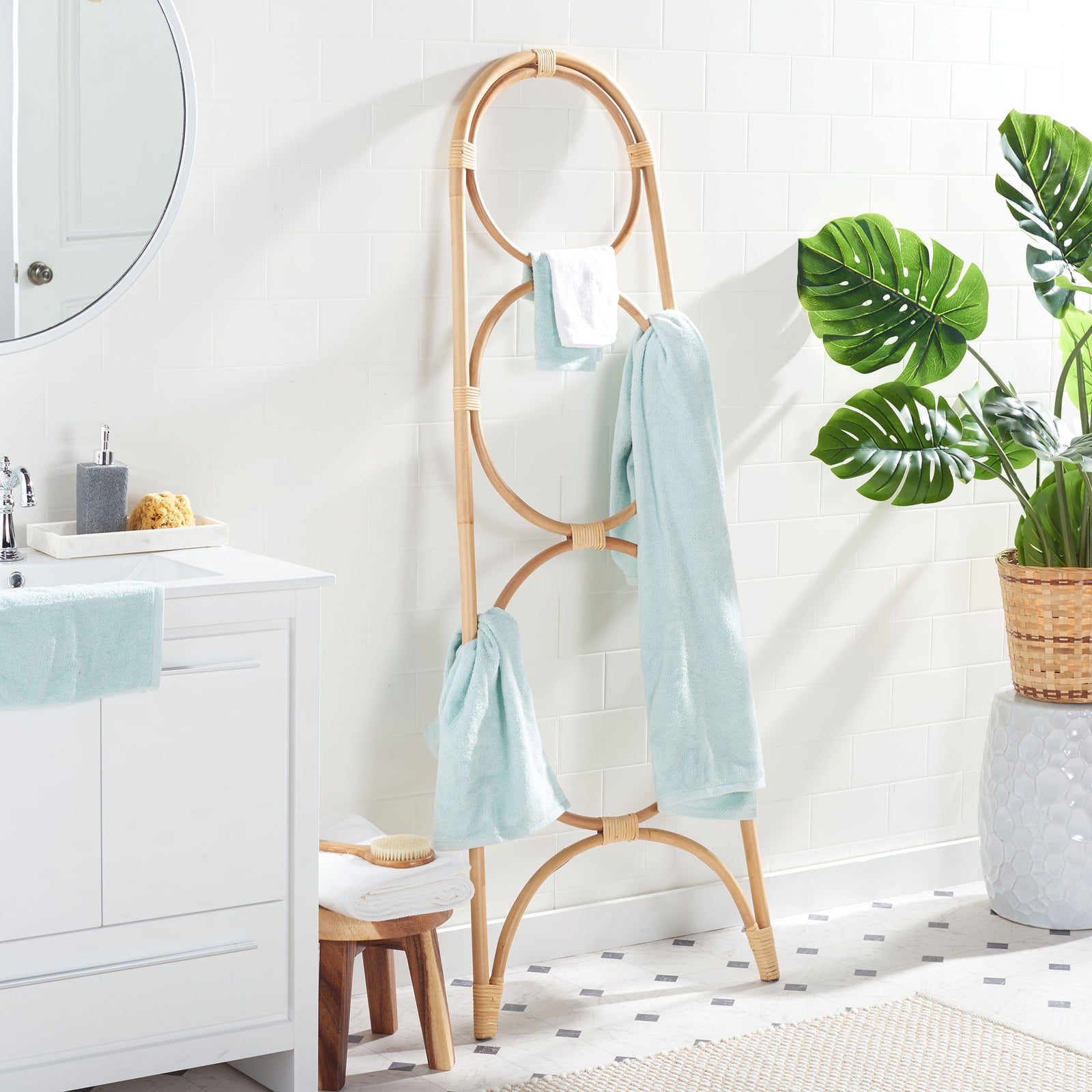 Light blue towels drape across the natural rattan stand's airy circular rails. || STG6501A || side_room