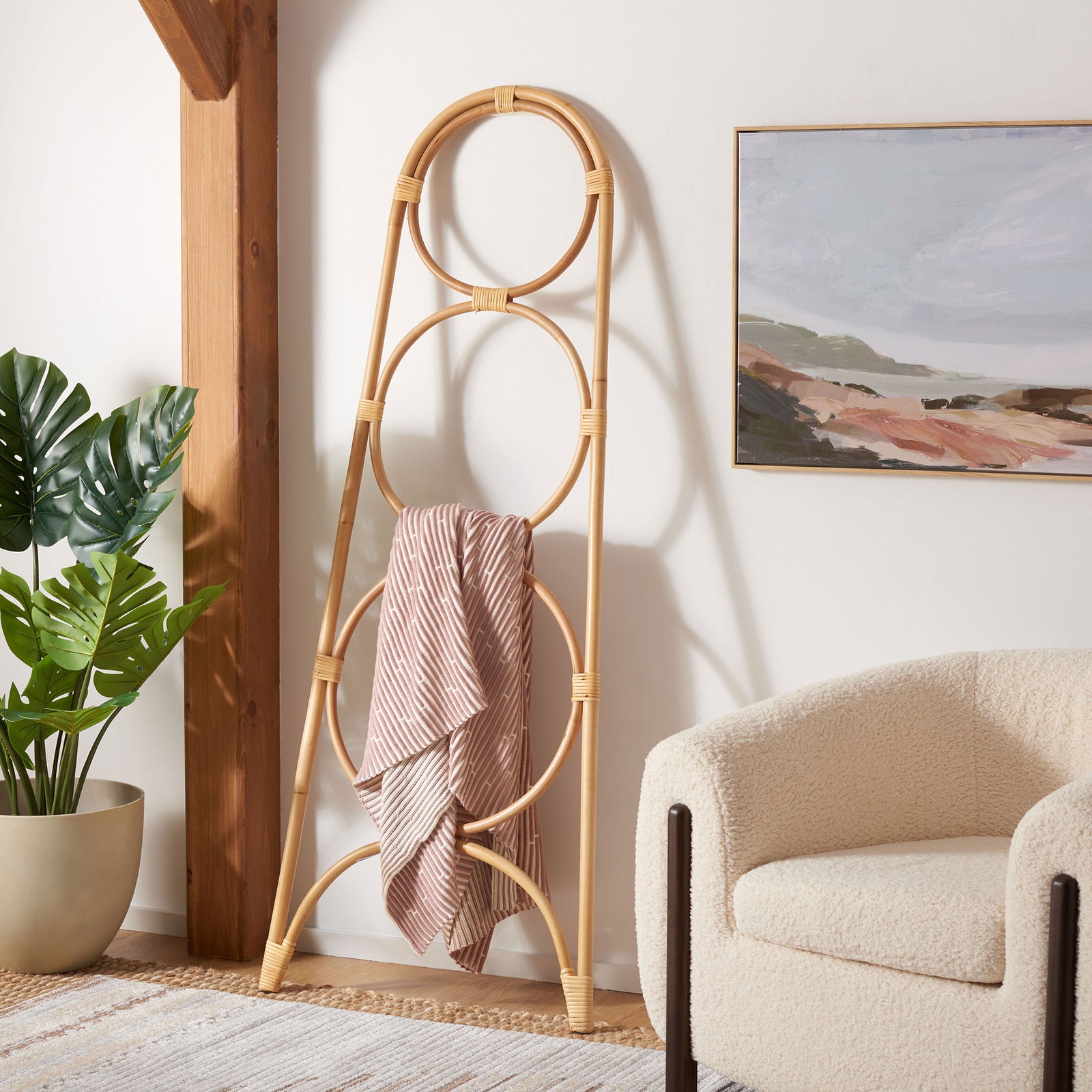 A blush striped throw softens the natural rattan stand's open circular frame. || STG6501A || front_angle_room