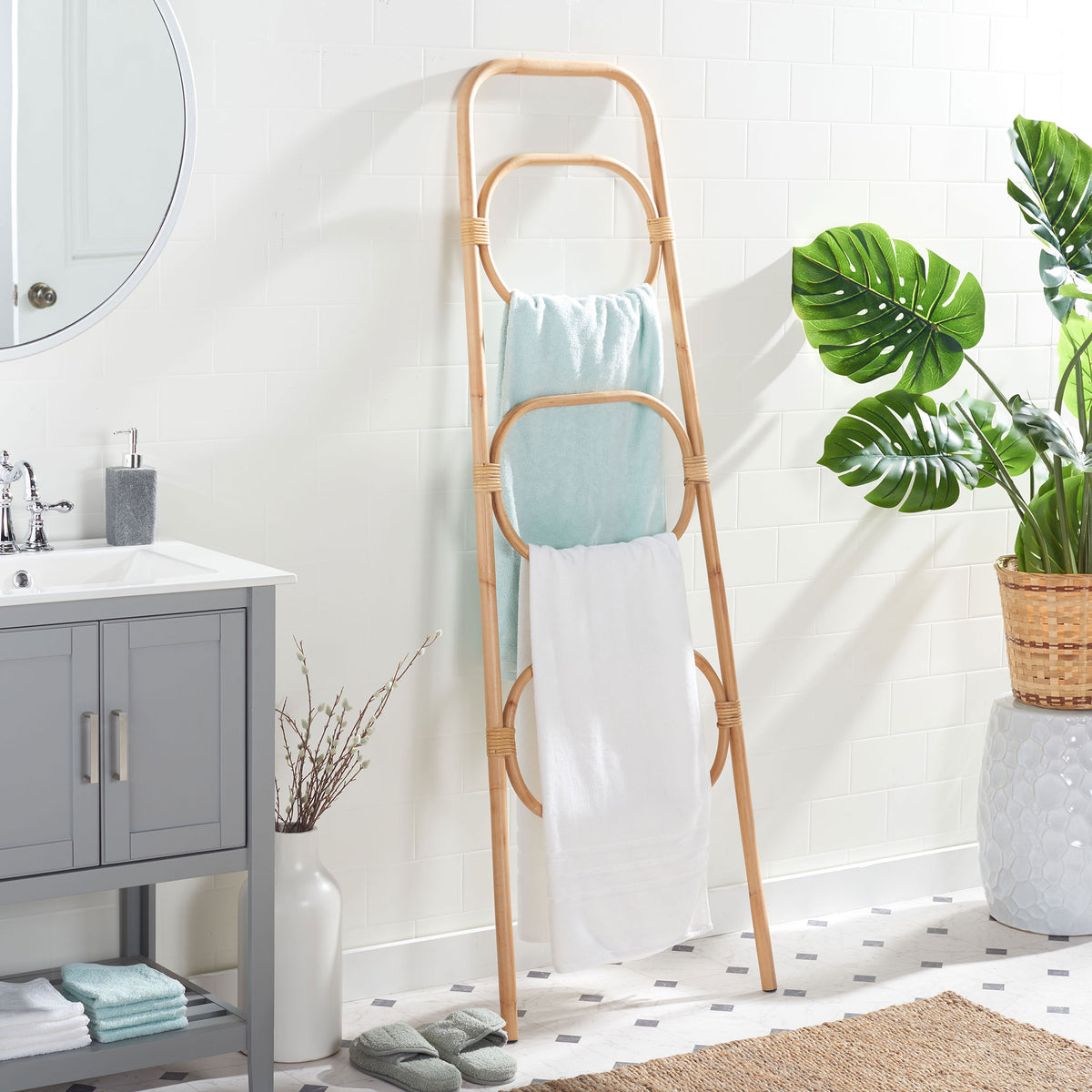 Three natural rattan tiers keep white and blue bath towels organized beside a vanity