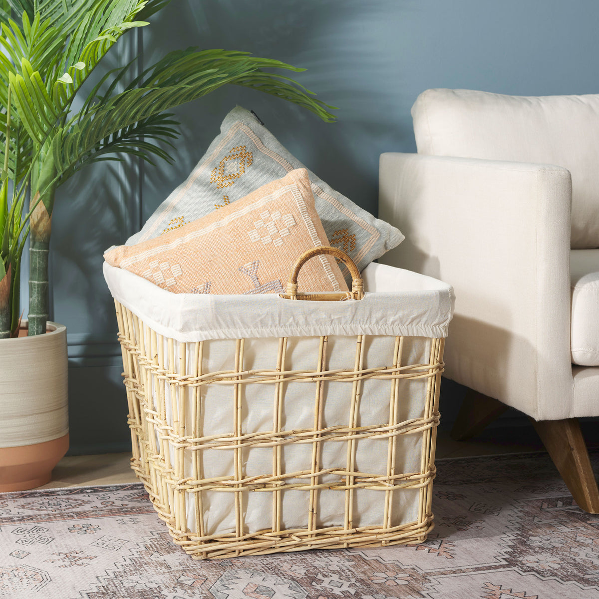 White-lined rattan basket holds throw pillows beside an upholstered chair || STG6503A || front_angle_room