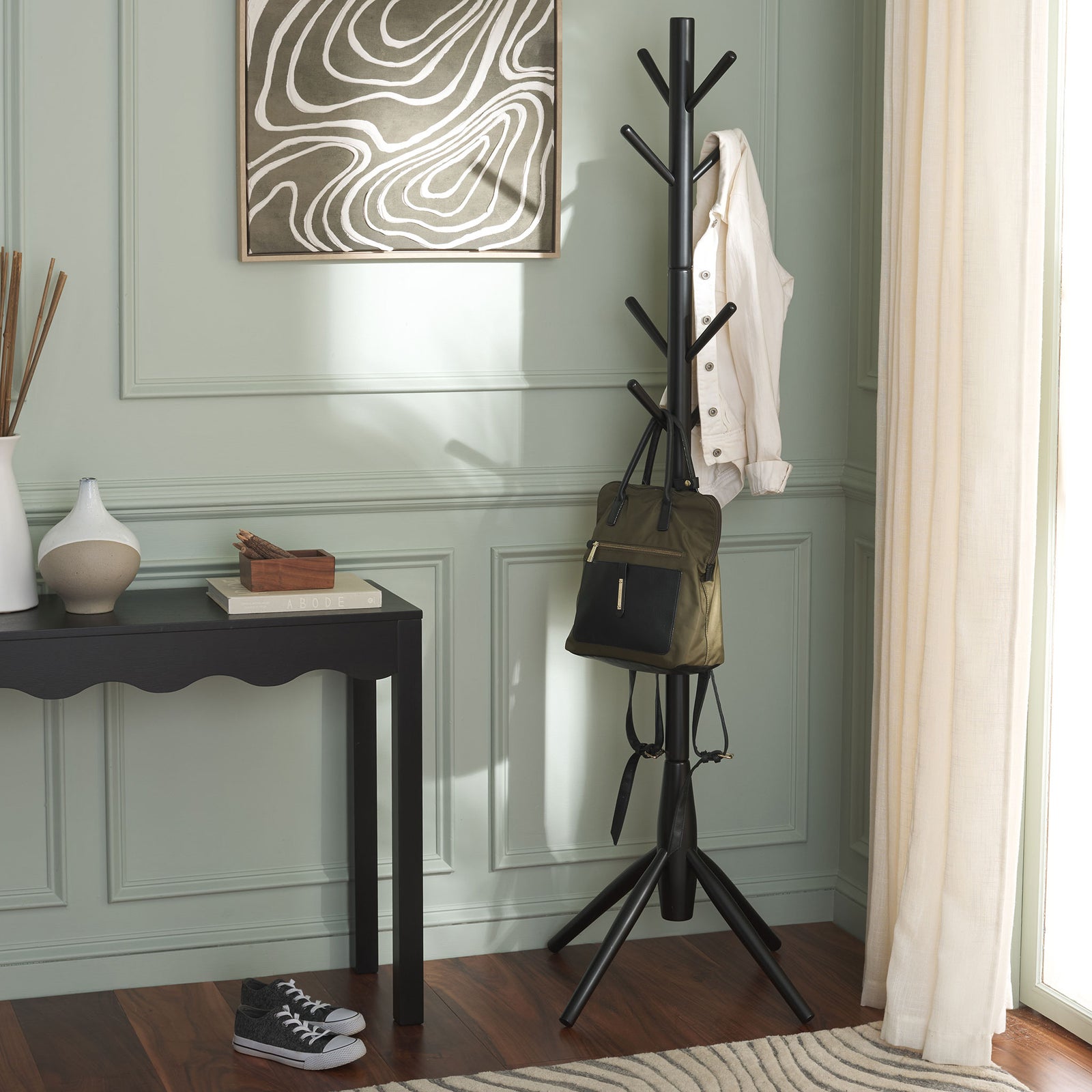 Matte black coat stand holds a jacket and backpack beside an entryway table || STG8500A || front_room