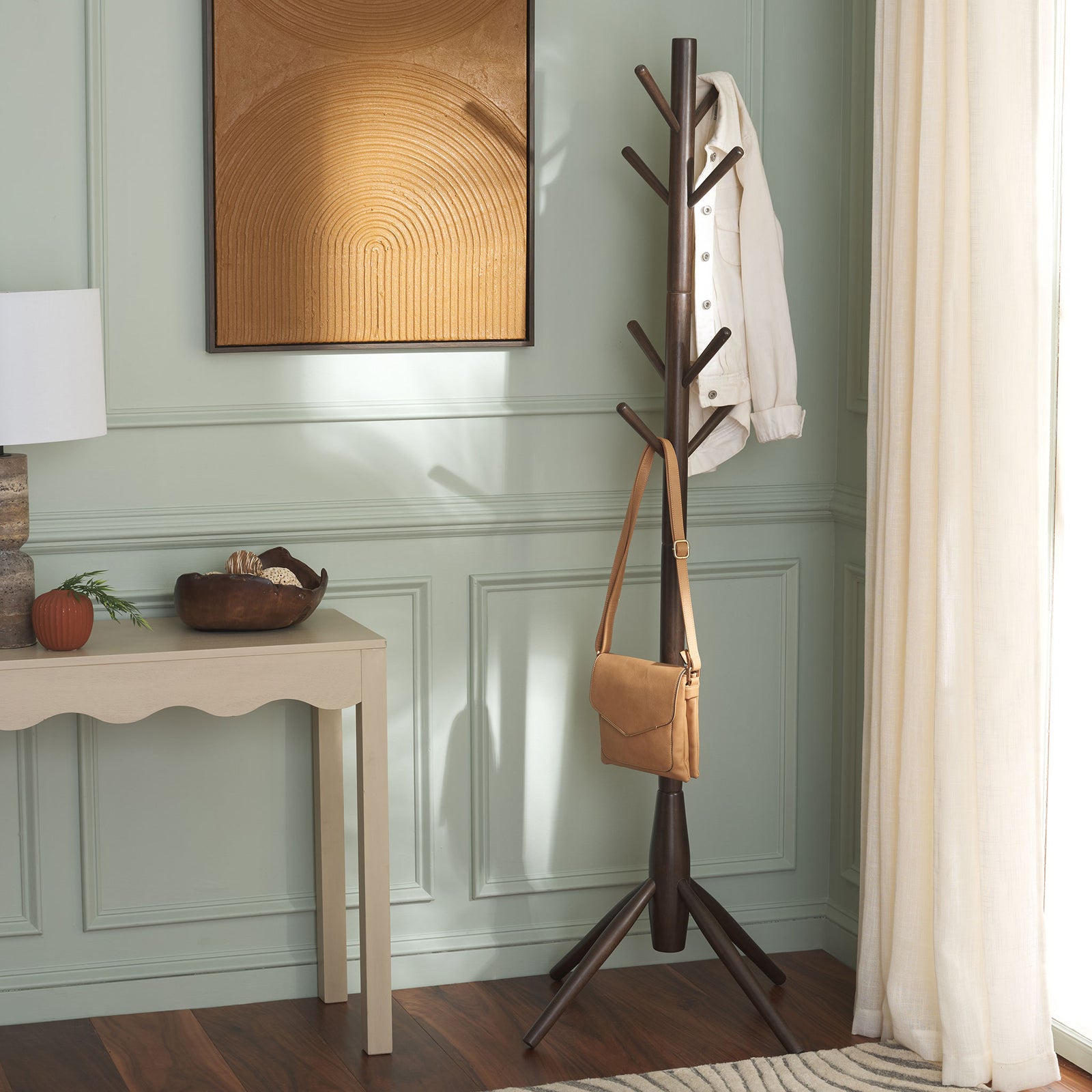 Dark walnut coat stand holds a jacket and tan bag beside an entryway table || STG8500B || front_room