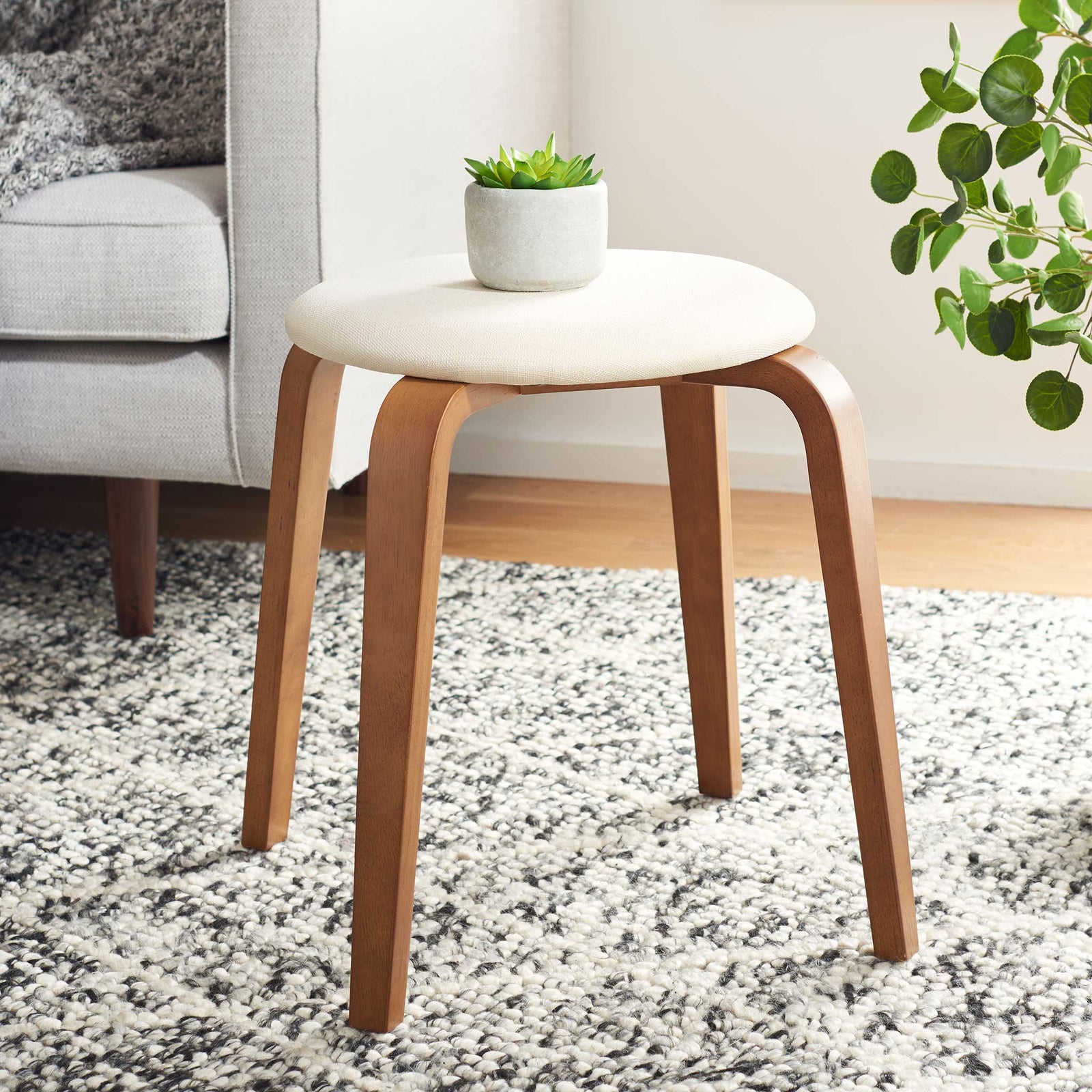 Modern stool warms the room with walnut tones and a cream linen seat, perfect beside a sofa || STL1001B || front_angle_room