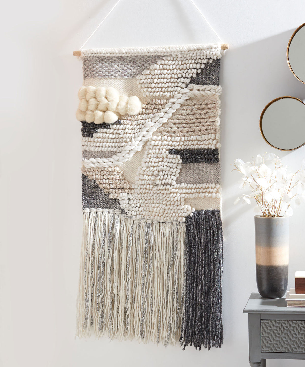 Ivory and charcoal wall hanging mixes chunky abstract stitches with dramatic split-color fringe. || SWA143-2 || front_room
