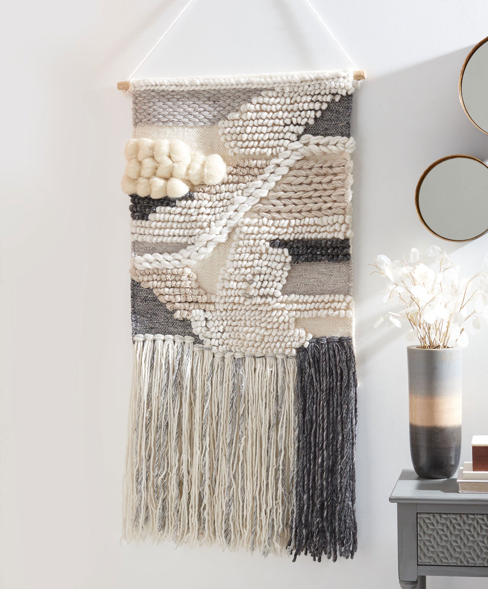 Ivory and charcoal wall hanging mixes chunky abstract stitches with dramatic split-color fringe. || SWA143-2 || front_room