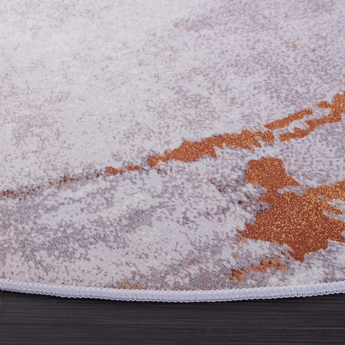 Stitched edge and softly textured pile highlight the gray and rust abstract pattern. || TAC801P-6R || corner_studio