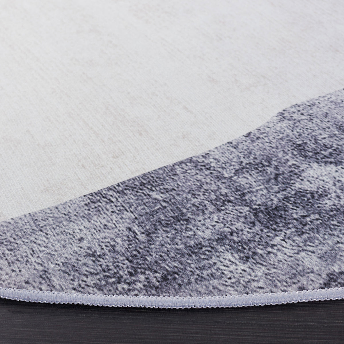 Low-profile edge shows crisp binding and the rug's gray, teal, and gold abstract pattern || TAC820F-6R || detail_room
