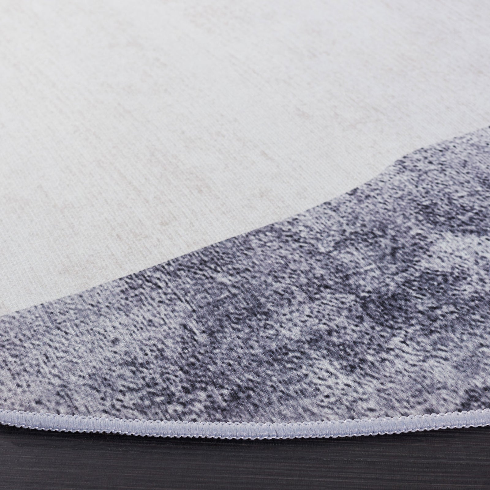 Low-profile edge shows crisp binding and the rug's gray, teal, and gold abstract pattern || TAC820F-6R || detail_room