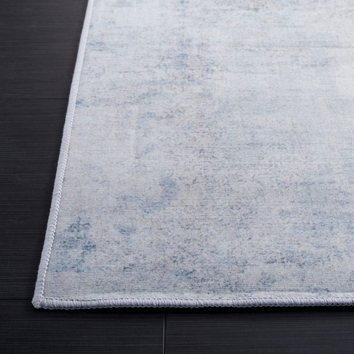 Neatly serged edge and subtle mottled pattern in gray and blue elevate the rug's refined look || TAC833F-5 || corner_room