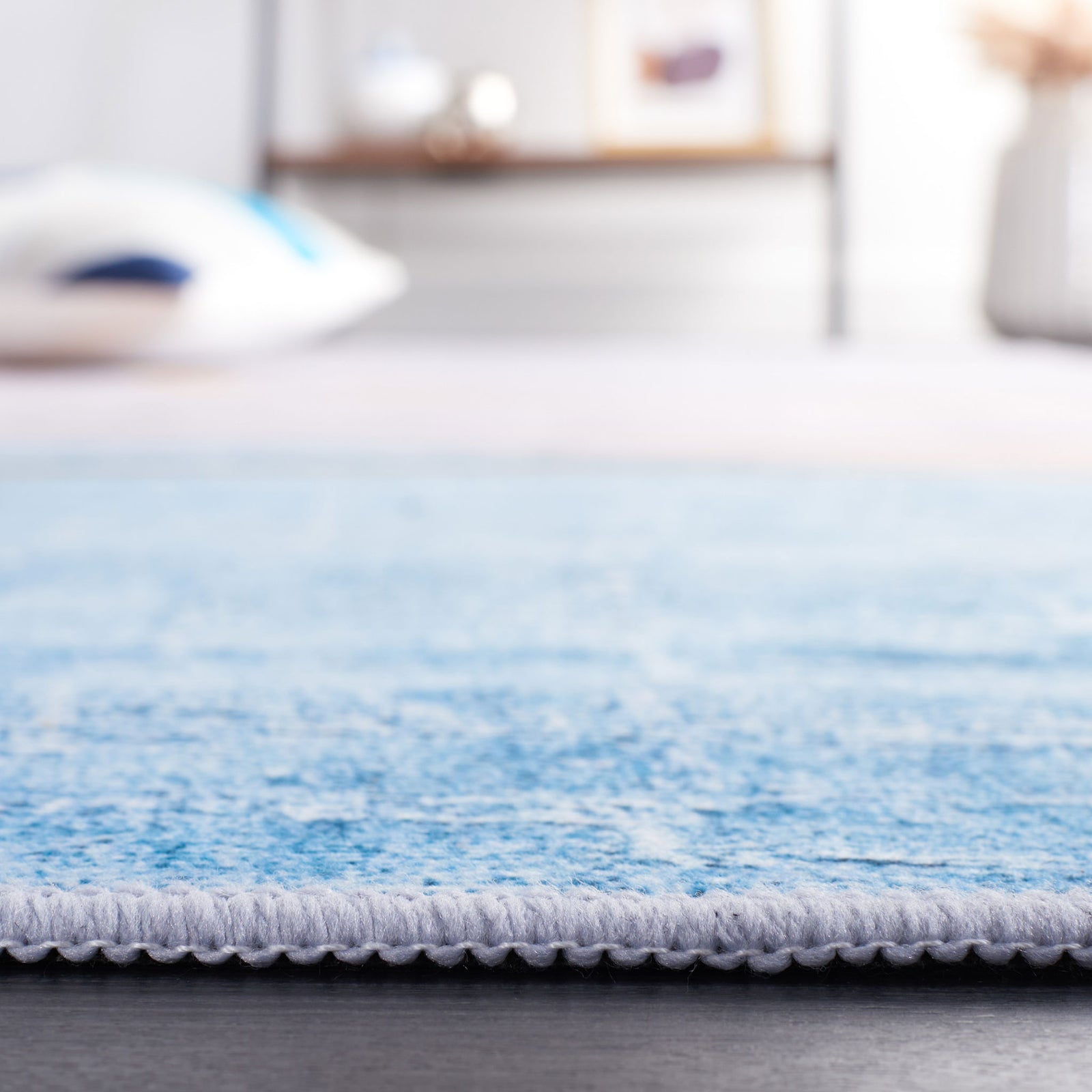 Low-profile washable rug with neatly serged edge in sky blue. || TAC834B-5 || detail_room