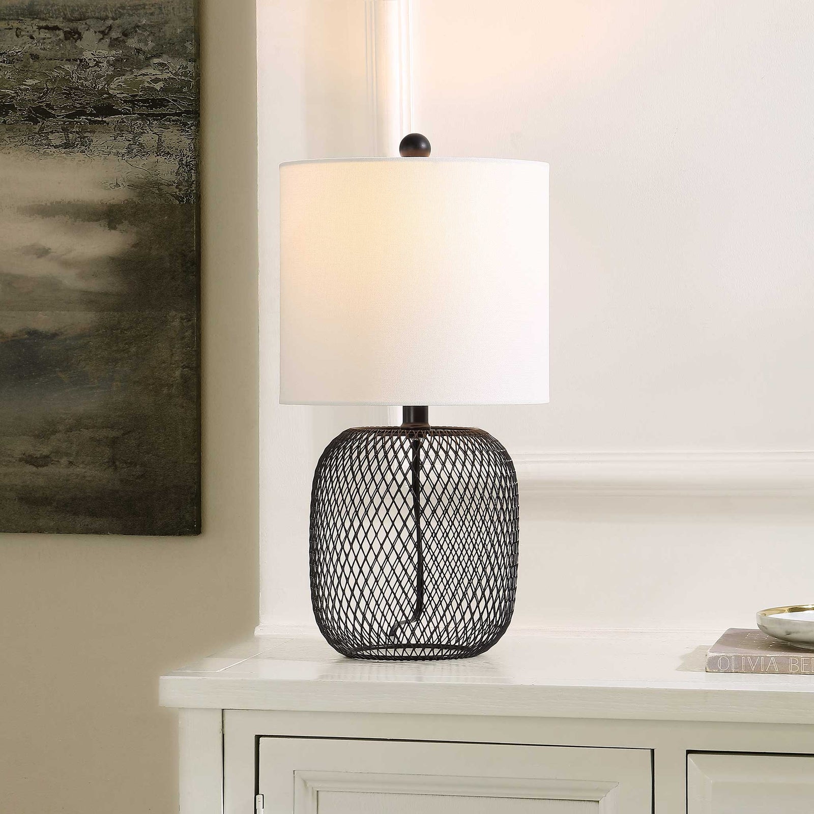 Glowing through a white shade, the black mesh base casts soft warmth that elevates your space. || TBL4470A || front_angle_on_room