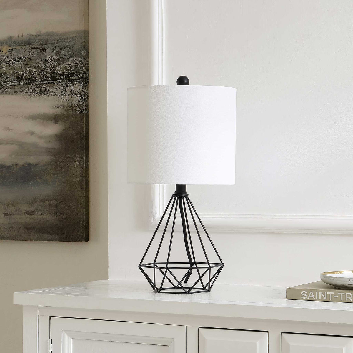 Sculptural black iron lamp with a white shade adds crisp modern contrast to consoles and nightstands. || TBL4489A || front_angle_room