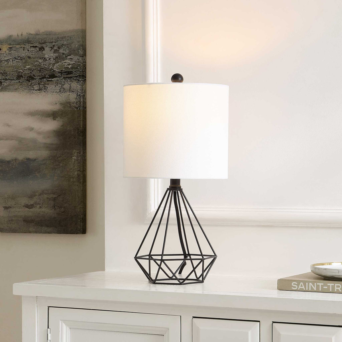 Soft ambient light glows from a white shade atop a faceted black wire base for sleek, modern warmth. || TBL4489A || front_angle_on_room