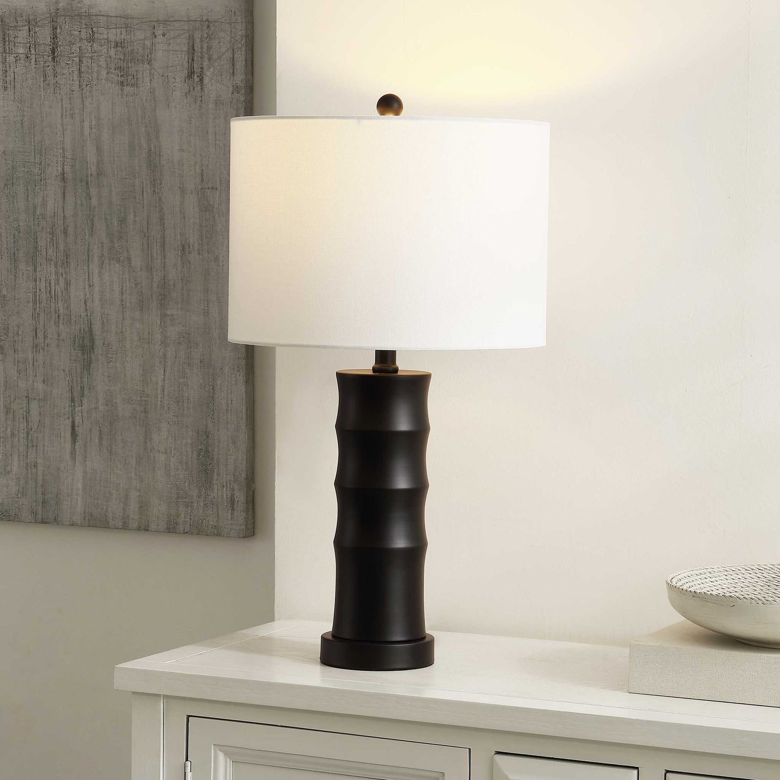 Glowing white shade softens the bold black iron base, creating a cozy ambient accent || TBL4493A || front_angle_on_room