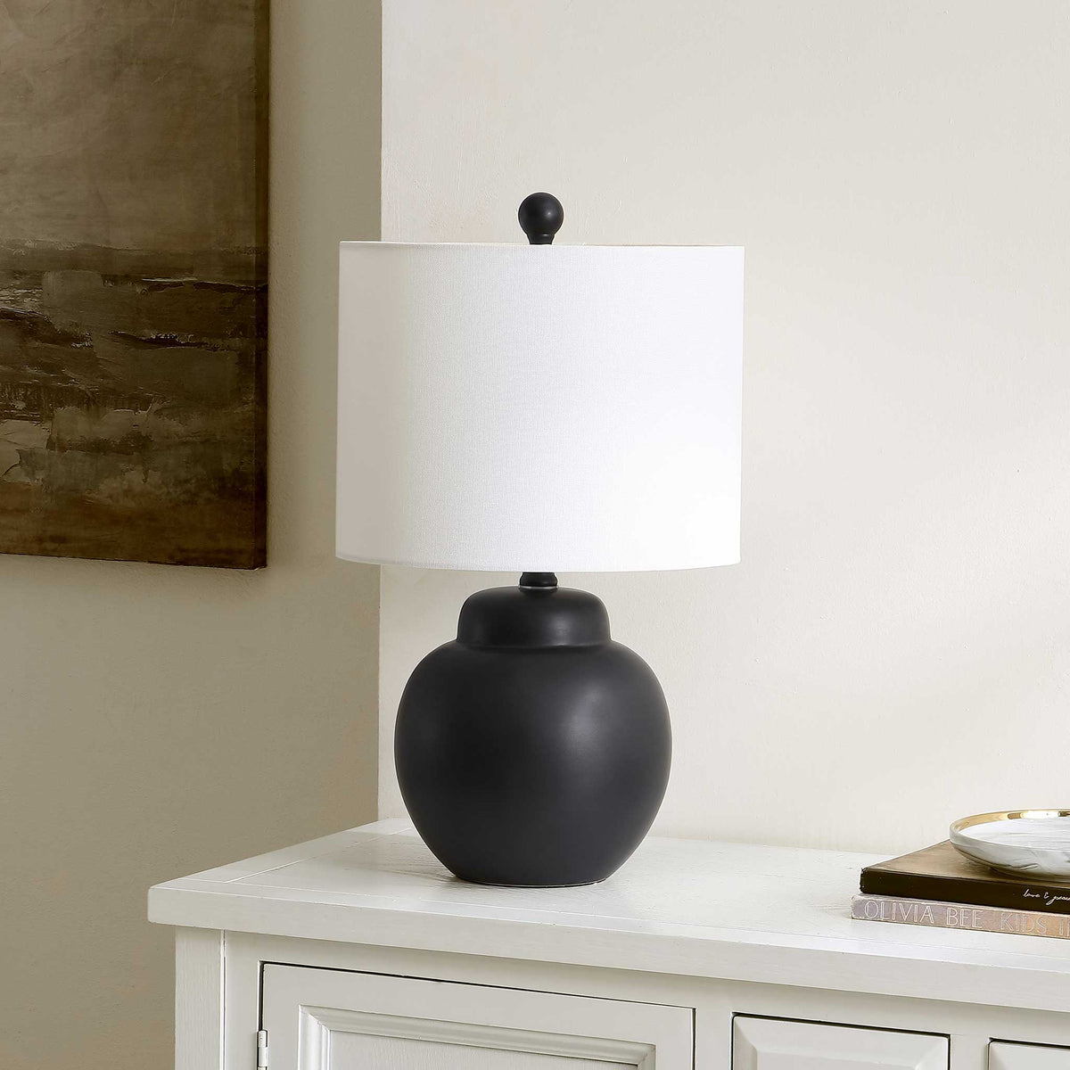 Sleek black ceramic lamp with smooth rounded silhouette and a crisp white drum shade || TBL4513A || front_angle_room