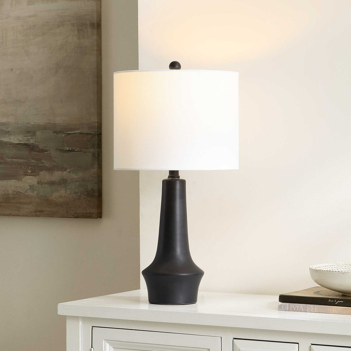 Soft ambient glow from a black ceramic table lamp through a white fabric shade. || TBL4514A || front_angle_on_room