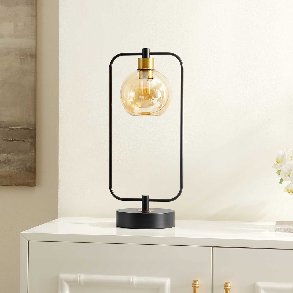 Modern lamp adds sculptural style with a black frame and amber globe on a crisp console || TBL4524A || front_angle_room