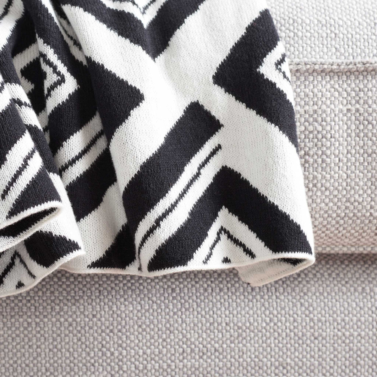 Chevron edge of the black and ivory throw with bold lines and a soft knit texture. || THR403A-5060 || corner_room