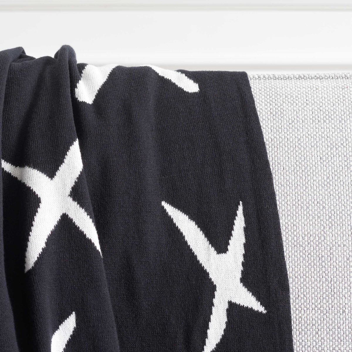 Plush cotton knit delivers inviting warmth with bold ivory Xs on a deep black ground